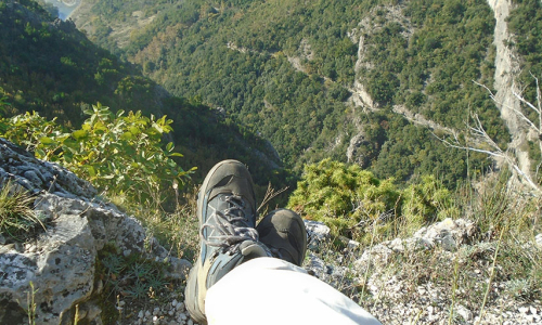 a-person-standing-on-top-of-a-mountain-with-their-feet-in-the-air