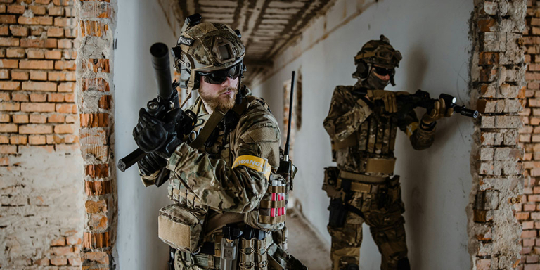 Two men playing milsim in military uniforms carrying BB rifles and milsim aciton cameras